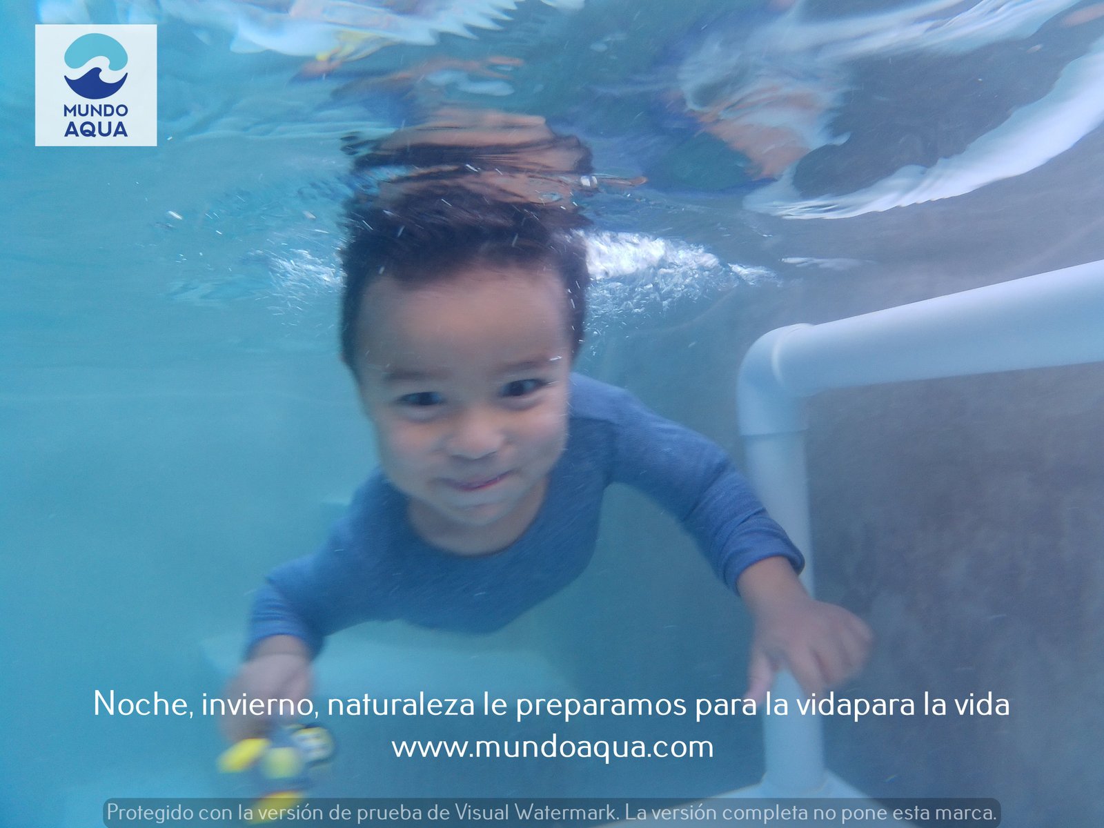 Baby playing happily with a green toy underwater in Mexico